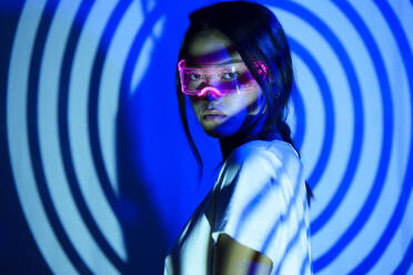 Young woman with futuristic glasses under spiral shadow - JSMF02451