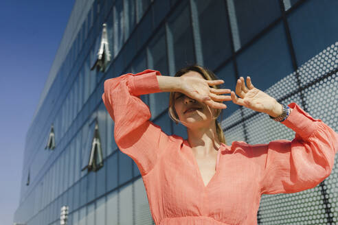 Frau bedeckt Augen mit Händen vor einem Gebäude - SEAF01334