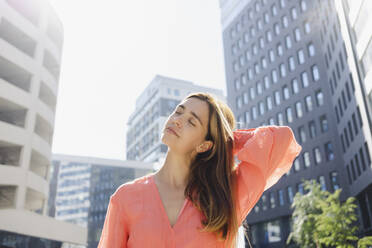 Woman with eyes closed in front of modern building - SEAF01350