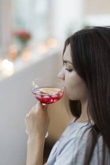 Junge Frau trinkt Rotwein auf dem Balkon - ONAF00166