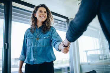 Recruitment manager shakes her hand with male candidate as he gets the job. Businesswoman handshake with a man in office meeting room. - JLPSF05186