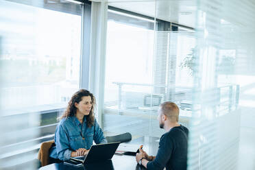 Businesswoman interviewing male job candidate in meeting room. Man sitting in a conference room for a job interview. - JLPSF05307