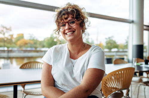 Portrait of a confident woman with eyeglasses in office. Smiling businesswoman looking at camera. - JLPSF05340