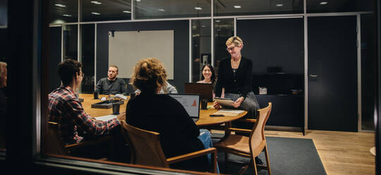 Ein Team von Geschäftsleuten, die an einem Konferenztisch zusammensitzen und diskutieren. Eine heterogene Gruppe von Geschäftsleuten trifft sich im Sitzungssaal. - JLPSF05362