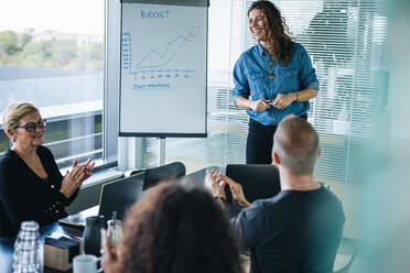 Business-Team klatscht für eine Kollegin nach ihrer erfolgreichen Präsentation. Business-Kollegen applaudieren nach einer guten Präsentation im Büro Sitzungssaal. - JLPSF05386