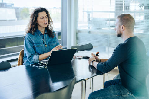 Eine Arbeitgeberin führt ein Vorstellungsgespräch mit einem Bewerber. Eine Geschäftsfrau interviewt einen jungen Mann für einen Job im Büro. - JLPSF05411