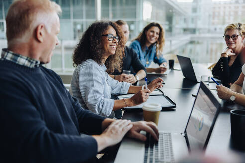 Multi-ethnic business people smiling during a meeting in conference room. Team of professionals having meeting in boardroom. - JLPSF05414