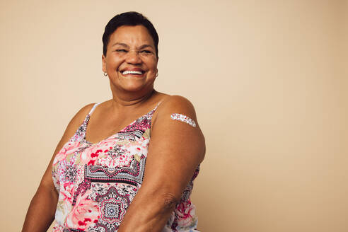 Porträt einer reifen Frau, die nach einer Impfung lächelt. Frau schaut weg und lächelt, nachdem sie geimpft wurde. - JLPSF05456