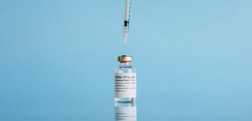 Fläschchen mit Spritze auf reflektierender Oberfläche, Coronavirus-Impfstoff mit Injektion auf blauem Hintergrund. - JLPSF05519