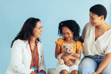 Small girl having medical exam by female doctor while being with her mother in the clinic. Pediatrician examining a girl patient. - JLPSF05535