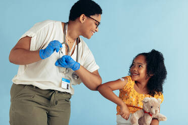 Ein Arzt gibt einem Mädchen nach einer Impfung in der Klinik einen Ellbogenstoß. Ein Arzt und eine Patientin begrüßen sich mit einem Ellbogenstoß. - JLPSF05545