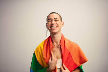 Fröhlicher Transgender-Mann mit Gay-Pride-Flagge. Gender-Fluid-Mann mit Igbt-Flagge vor weißem Hintergrund. - JLPSF05662