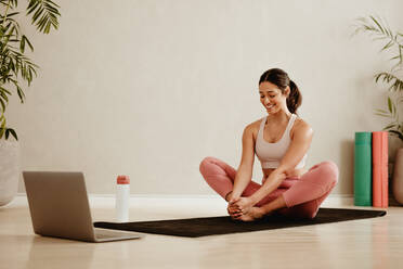 Woman following online workout session at home. Female watching online exercise class and exercising at home. - JLPSF05732