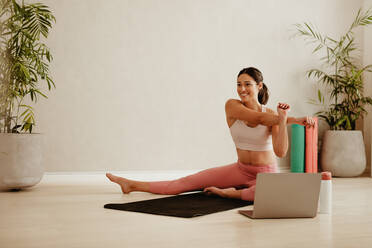 Woman doing fitness workout on studio. Female in sportswear working arms stretching exercising watching online videos on laptop. - JLPSF05738