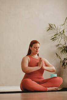Frau macht Meditation Yoga-Übung im Fitness-Studio. Frau sitzt auf Meditation Pose mit Händen verbunden im Fitness-Studio. - JLPSF05751