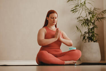 Frau trainiert zu Hause, macht Yoga-Übungen auf der Matte. Fitness-Frau meditiert im Lotussitz. - JLPSF05752