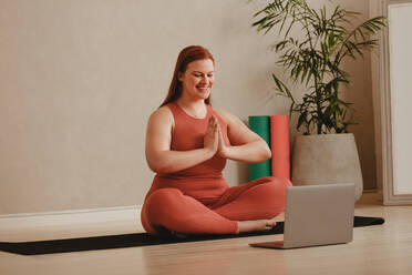 Happy young chinese woman sitting yoga pose and watching