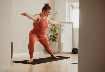 Fitte Frau, die zu Hause auf einer Fitnessmatte trainiert. Frau in Sportkleidung beim Yoga-Workout im Fitnessstudio. - JLPSF05778