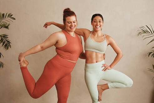 Women sportswear standing together on one leg at fitness studio. Females exercising at health club. - JLPSF05794