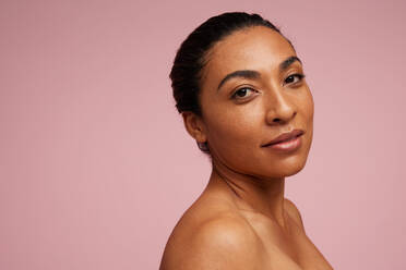 Portrait of a mixed race woman with beautiful skin. Female model staring at camera over pink background. - JLPSF05800
