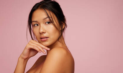 Portrait of a asian female model with healthy skin on pink background. Natural beauty looking away with hand on chin. - JLPSF05820