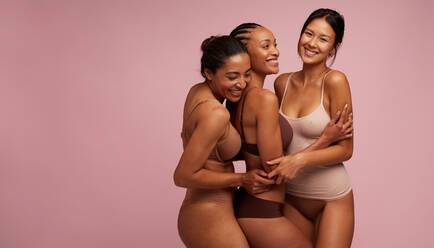 Female friends dancing cheerfully while wearing underwear. Two body  positive young women celebrating their natural bodies against a studio  background. Two women feeling comfortable in their bodies. stock photo