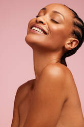 Nahaufnahme eines lächelnden weiblichen Models mit gesunder Haut auf rosa Hintergrund. Afrikanische Frau mit makelloser Haut. - JLPSF05839