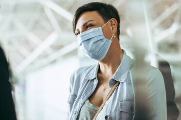 Woman traveler wearing face mask at airport. Female passenger during corona virus pandemic at airport. - JLPSF05945