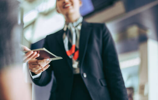 Beschnittene Aufnahme eines Flugbegleiters, der am Flughafen seinen Pass kontrolliert. Ein Flugbegleiter am Abfluggate kontrolliert den Pass eines Passagiers. - JLPSF05965