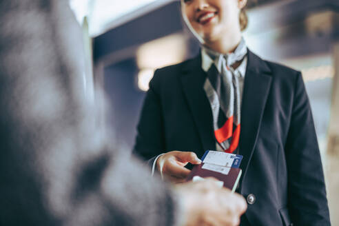 Abgeschnittene Aufnahme von Mitarbeitern der Fluggesellschaft, die einen Passagier am Check-in-Schalter kontrollieren. Flugbegleiter, der die Bordkarte eines Touristen am Flughafen kontrolliert. - JLPSF05968