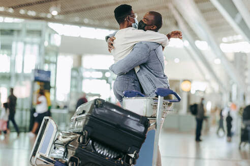 Ein afrikanisches Paar umarmt sich im Flughafenterminal. Ein Mann und eine Frau treffen sich bei der Ankunft am Flughafen nach der Pandemie-Sperre. - JLPSF05982