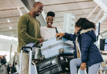 Vater und Mutter haben Spaß, während sie mit ihrer kleinen Tochter am Flughafen warten. Afrikanische Familie am Flughafen-Terminal wartet auf den Flug. - JLPSF06011