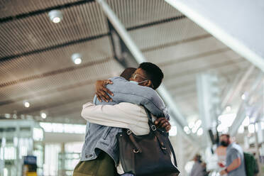 Couple embracing at airport during pandemic. Man hugging woman before bidding goodbye at airport terminal. - JLPSF06015