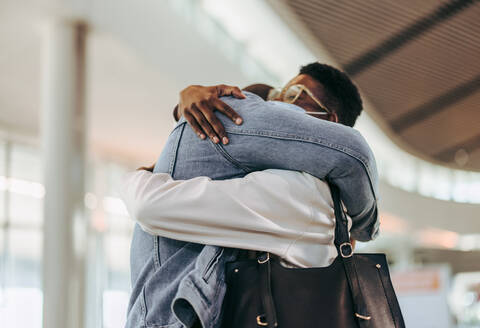 Passagier Paar geben warme Umarmung am Flughafen. Mann gibt warme Willkommensumarmung zu Frau am Flughafen Terminal. - JLPSF06016