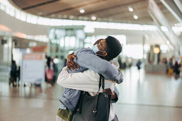 Traveler man and woman giving warm embrace at airport arrival gate. Woman getting warm welcome hug from man at airport. - JLPSF06017