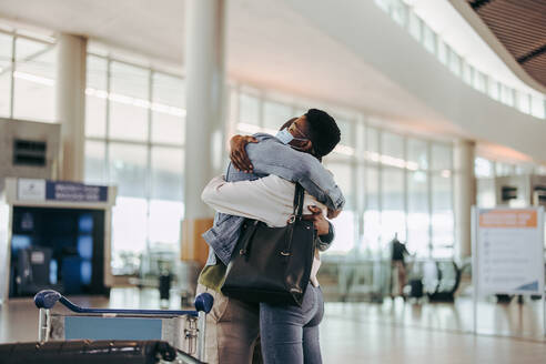 Ehepaar umarmt sich vor dem Abflug am Flughafen. Ehefrau umarmt ihren Mann zum Abschied am Abflugstor des Flughafens. - JLPSF06019
