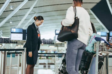 Flugbegleiter während der Pandemie, der eine Touristenfamilie am Flughafen empfängt. Flugpersonal am Flugsteig mit Passagieren mit Gesichtsmasken am Flughafen während der Pandemie. - JLPSF06027