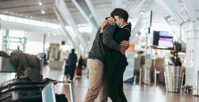 Paar, das sich am Flughafen trifft und umarmt. Mann und Frau treffen sich bei der Ankunft am Flughafen. - JLPSF06054