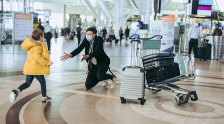 Kleiner Junge läuft seiner Mutter entgegen, die nach einer Reise während einer Pandemie am Flughafen ankommt. - JLPSF06064