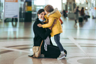 Mutter mit Gesichtsmaske trifft sich mit ihrem Sohn, nachdem sie von einer Geschäftsreise am Flughafen angekommen ist. - JLPSF06069