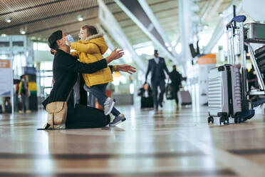 Mutter empfängt ihr Kind mit offenen Armen am Flughafen während der Pandemie. Frau mit Gesichtsmaske trifft ihren Sohn am Flughafen. - JLPSF06071
