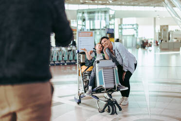 Mutter und Sohn posieren für ein Foto am Flughafen. Ein Mann fotografiert seine Familie im Flughafenterminal. - JLPSF06088