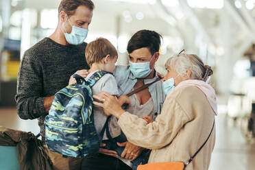 Großmutter trifft Familie am Flughafen nach langer Pandemie-Sperre. Ältere Frau und Familie mit Gesichtsmasken bei der Ankunft am Flughafen. - JLPSF06097
