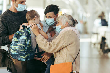 Ältere Frau im Gespräch mit ihrem Enkelkind am Flughafen. Frau mit ihrem Sohn und Ehemann trifft sich mit ihrer Mutter am Flughafen in Pandemie. - JLPSF06098