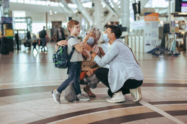 Ältere Frau mit Tochter und Enkel, die am Flughafen auf ihren Flug warten. Familie, die mit dem Flugzeug reist, wartet am Flughafen während der Pandemie. - JLPSF06104