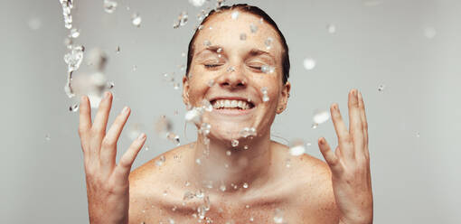 Close up of young woman with freckles on skin. Happy woman splashing water on face. - JLPSF06130