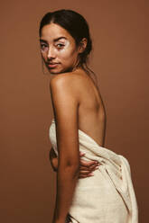 Side view portrait of woman having vitiligo standing against brown background. Confident young woman with skin disorder representing body positivity. - JLPSF06163