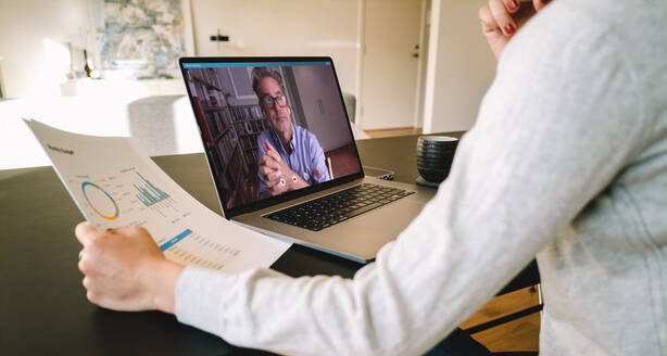 Geschäftspartner, die einen Laptop für ein Online-Meeting per Videoanruf verwenden. Geschäftsfrau, die von zu Hause aus arbeitet und einen Videoanruf an einen Geschäftspartner mit Laptop tätigt. - JLPSF06309