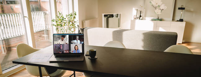 Laptop auf dem Tisch mit einem Videogespräch auf dem Bildschirm im Wohnzimmer. Menschen nutzen VoIP, um sich miteinander zu verbinden. - JLPSF06311
