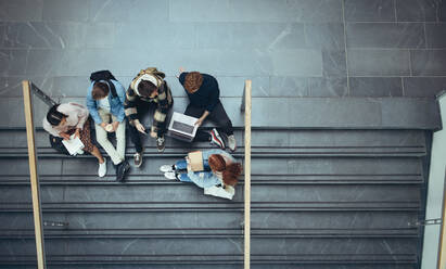 Blick von oben auf Studenten, die auf einer Treppe in einem College lernen. Junge Leute verbringen Zeit miteinander nach dem Unterricht. - JLPSF06325